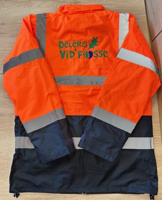 Gilet de travail haute visibilité orange et bleu marine, bandes réfléchissantes. Logo au dos: DÉLÉRIS VID' FOSSE avec feuille de chêne.