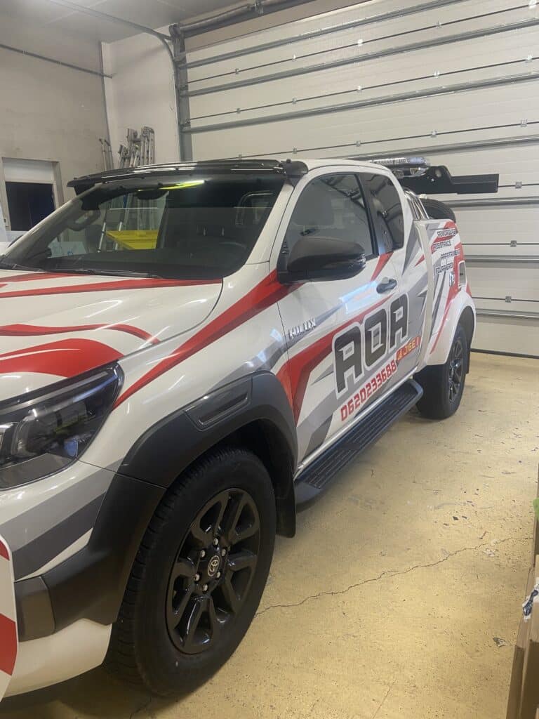 Pick-up Toyota Hilux de remorquage RDA avec logo rouge et gris, services d'assistance et numéro 0620233688.