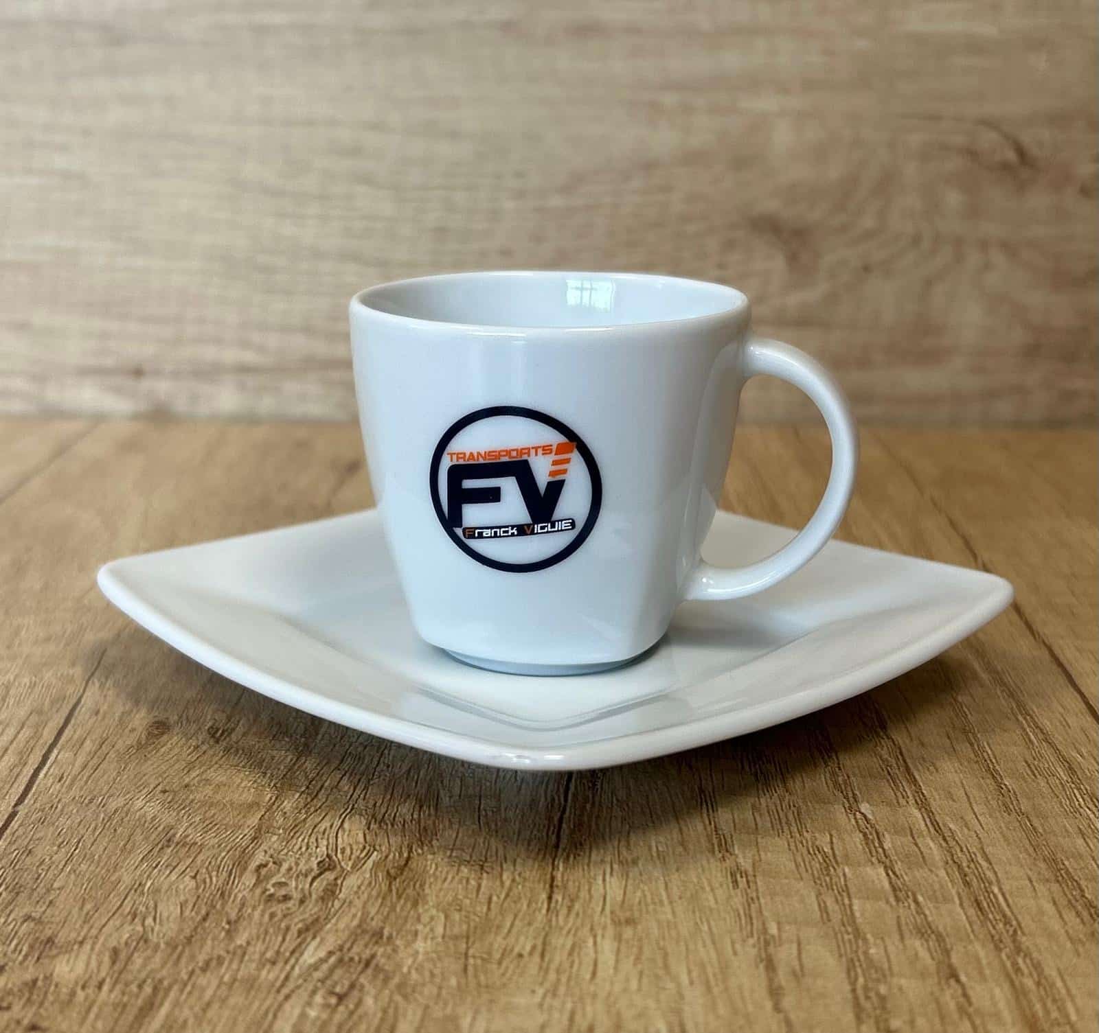 Tasse Espresso Transports FV Franck Viguie Personnalisée Tasse à café blanche et soucoupe carrée avec logo Transports FV Franck Viguie sur une table en bois.